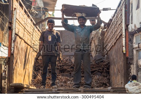 MUMBAI, INDIA - 12 JANUARY 2015: Two men load metal on back of recycling truck. Dharavi slum has a increasingly large recycling industry.