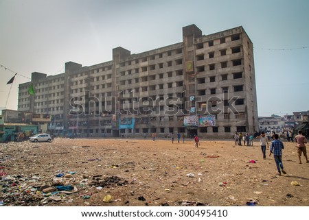 MUMBAI, INDIA - 12 JANUARY 2015: Unfinished empty apartment block and dirty field with people in Dharavi slum. Dharavi is one of the largest slums in the world.