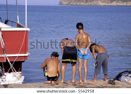 young boys on pier looking at friend in sea