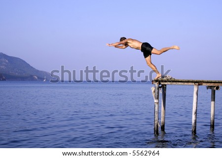 man jump diving from pier into sea