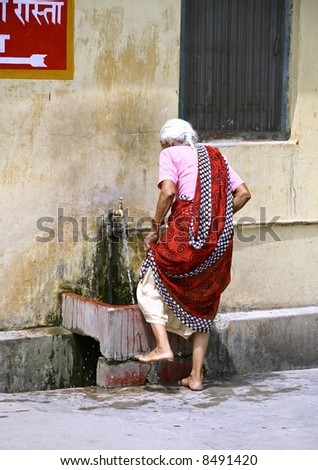 old lady washing her feet, rishikesh, india