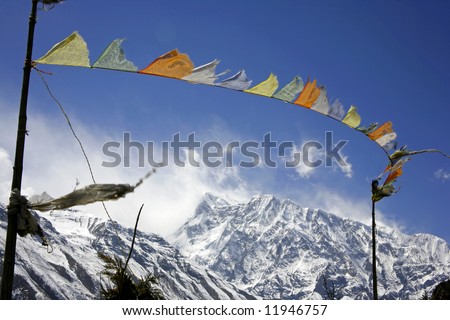 praying flags floating in the wind in front of the annapurnas, nepal
