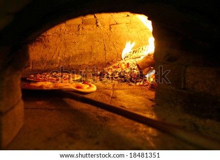 Pizzas baking in an open firewood oven