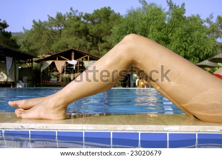 woman\'s beautiful thin legs alongside pool in summer