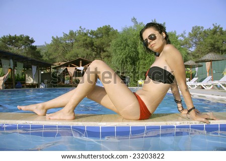 young woman posing on side of swimming pool