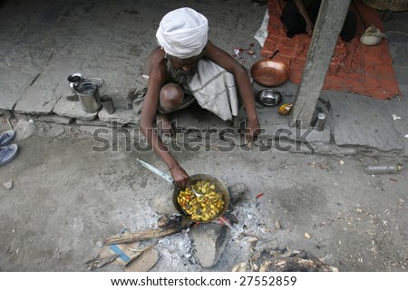 TATOPANI, NEPAL - APRIL 1: Old sadhu prepares a vegetarian meal on open fire on the Annapurna trail, Tatopani, Nepal April 5, 2008. Annapurna trail is well known for its trekking activities.