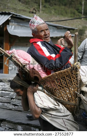 ANNAPURNA, NEPAL - APRIL 5: Old Nepali man being carried by porter to his village in Annapurna, Nepal April 5, 2008. Annapurna trail is well known for its trekking activities.