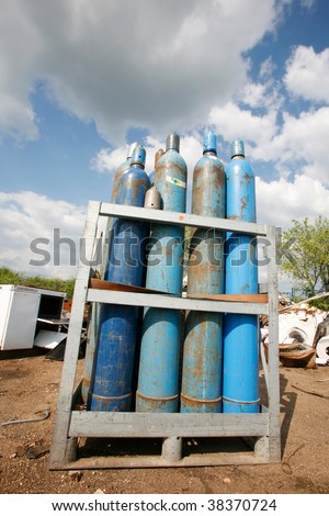 Blue gas bottles stored in junkyard site