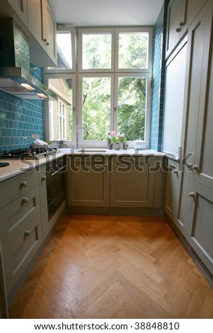 Modern kitchen with turquoise tiles on wall looking onto garden