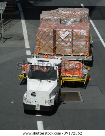 Airport vehicle transporting cargo to airplane on runway