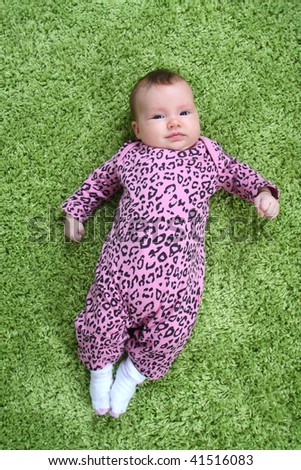 baby laying on his back on green carpet in pink leopard outfit