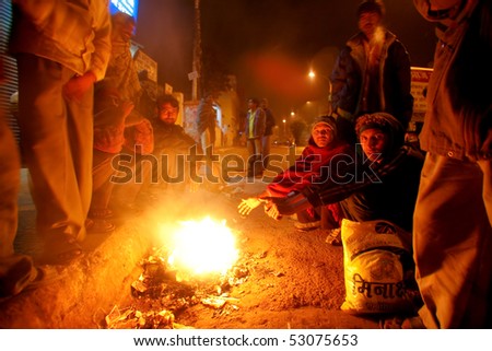 DELHI - JANUARY 18: Crowd of day workers wait around street fire in early morning on January 18, 2008 in Delhi, India. These men are not paid more than 2 dollars a day.