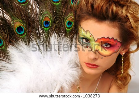 beautiful girl with a painted mask and peacock\'s fun