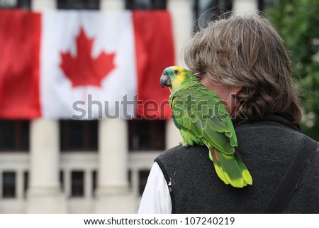 OTTAWA, CANADA - JULY 1: A man with a parakeet on Canada Day, July 1, 2012 in Ottawa, Ontario. Canada Day is a national holiday, and is celebrated each July 1st across the country.