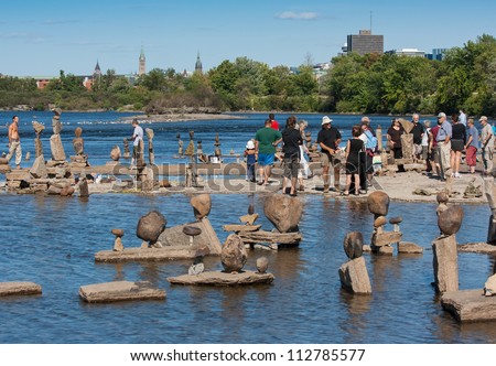 OTTAWA, CANADA - AUGUST 18: People admiring the sculptures at the International Stone Balance Festival on the Ottawa River at Remic Rapids on August 18, 2012 in Ottawa, Ontario.