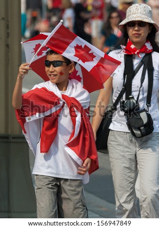 OTTAWA, CANADA - JULY 1: An unidentified Asian boy waving a Canadian flag during Canada Day on July 1, 2013 in downtown Ottawa, Ontario.