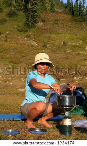 Filipino woman using camp stove in wilderness of British Columbia. Canada.