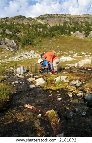 Two men filtering water from a mountain stream. British Columbia. Canada.