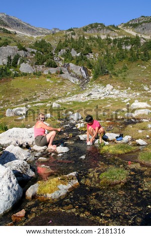 Women washing dishes in a mountain stream. British Columbia. Canada.