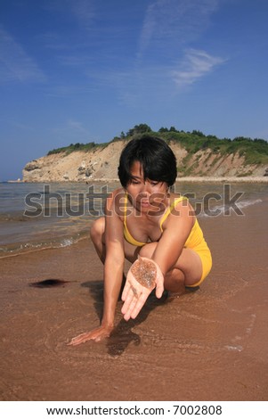 Filipino woman holding a fish on a beach. Cape Breton Highlands National Park. Nova Scotia. Canada.