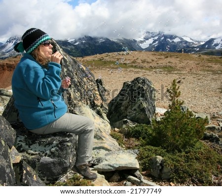 A woman blowing soap bubbles on Flute Summit near Whistler, British Columbia, Canada.