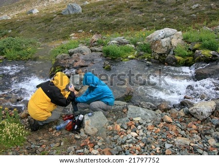 Two women filtering water from Russet Creek in Garibaldi Provincial Park, British Columbia, Canada.