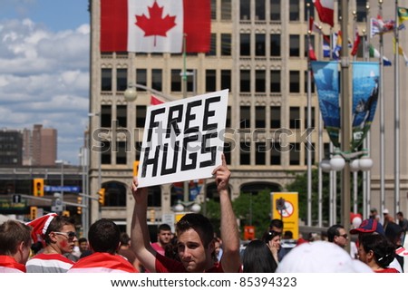 OTTAWA, CANADA – JULY 1: A man holds up a \'Free Hugs\' sign on July 1, 2011 in downtown Ottawa, Ontario. The crowd was celebrating Canada Day.