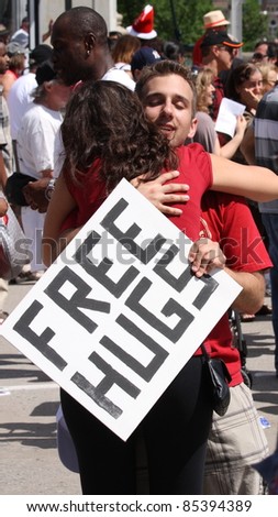 OTTAWA, CANADA – JULY 1: A young man with a \'Free Hugs\' sign embraces a stranger during Canada Day festivities on July 1, 2011 in downtown Ottawa, Ontario. Canada Day is an annual national holiday.