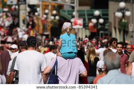 OTTAWA, CANADA – JULY 1: A girl being carried through the crowd during Canada Day on July 1, 2011 in downtown Ottawa, Ontario. Canada Day is a national holiday and is celebrated annually.