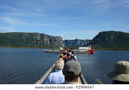 WESTERN BROOK POND, CANADA – JULY 19: Tourists heading towards tour boats on July 19, 2011 at Western Brook Pond in Gros Morne National Park, Newfoundland. The boats tour the fjords in the distance.