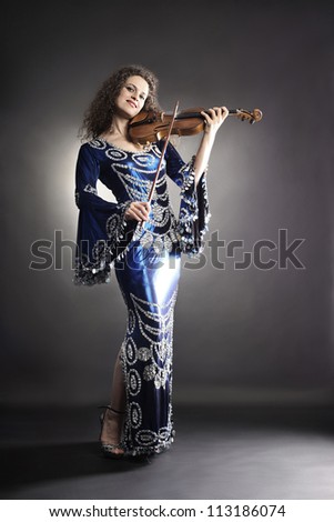 Beautiful woman with violin. Violinist performer in elegant dress