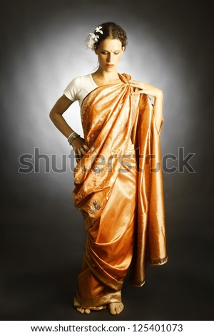 Woman in Indian fashion dress. National asian orange sari clothes on black