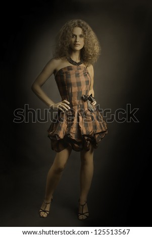 Fashion woman in elegant checked dress. Dark portrait of attractive brunette in checkered retro style