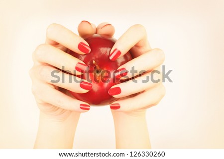 Manicure red nails. Woman\'s hand with ripe red apple.