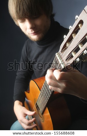 Acoustic guitar guitarist playing details. Musical instrument with musician hands. Focus is on the hand with instrument