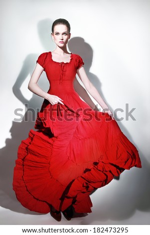 Fashion model in red dress. Elegant woman in long flying dress. Lady in red