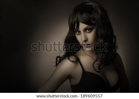 Dark portrait of brunette woman. Elegant fashion model in darkness