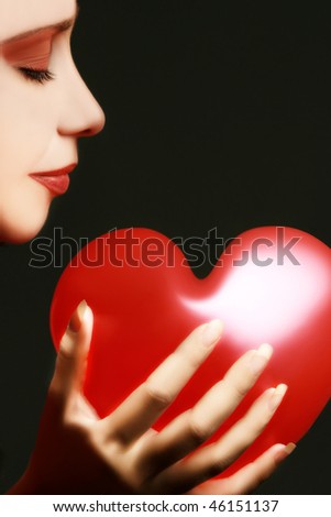 Beautiful woman face and red valentine heart on black background.