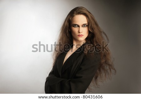 Fashion portrait of beautiful woman in black. Young attractive looking woman with long thick hair.