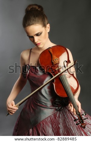 Violin playing beautiful woman violinist musician. Artistic portrait of melancholic fiddler