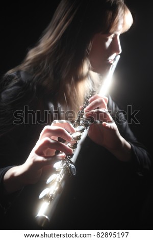 Flute playing flutist musician performer with bright musical instrument on the black background