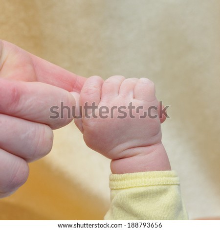 Baby hand reaches for the hand of the mother.