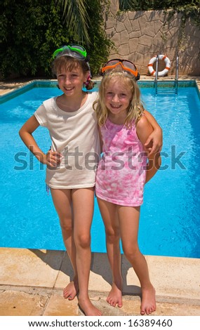 Two young sisters preparing to jump in the pool
