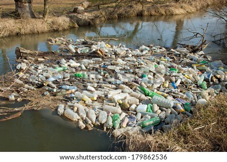 Environmental pollution. Plastic, glass and metal waste in river on early spring