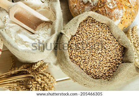 Loaf of bread, flour, wheat grain and wheat spike on table