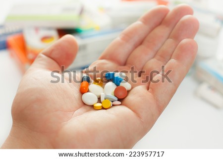 Man\'s hand hold many medicine, boxes of medicines in the background