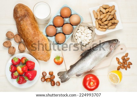 Allergy food concept - bread, milk, fruits, nuts, eggs and beans on wooden table