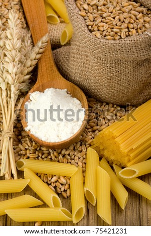 Raw pasta with wheat and flour on wood background