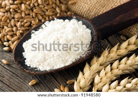Flour on old wooden spoon and wheat spike