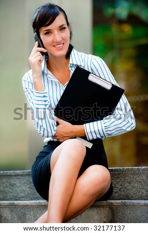 A beautiful businesswoman sitting down having a conversation on the phone in the city